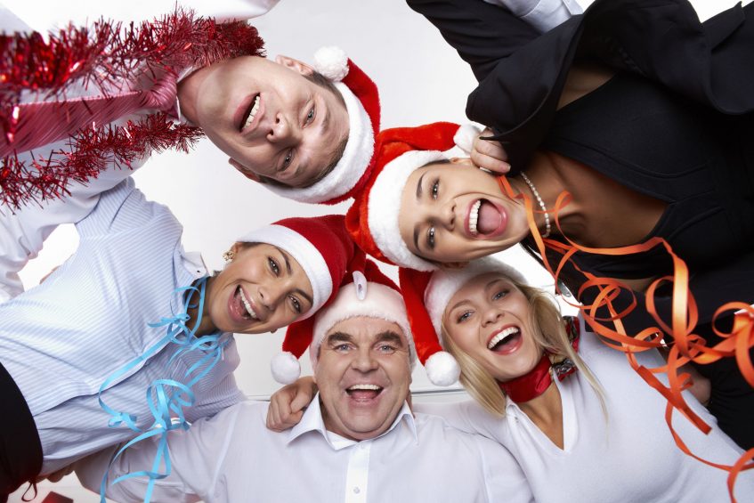 Portrait of smart colleagues in Santa caps wishing you Merry Christmas